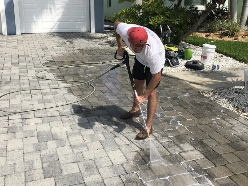 A crew member pressure cleaning a paver driveway