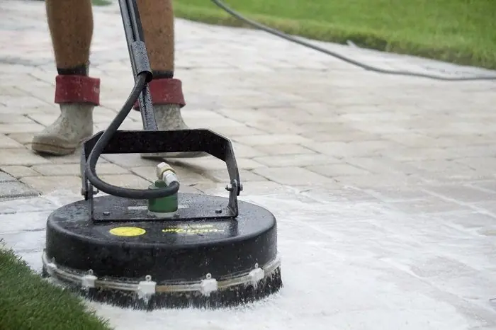 A surface cleaner running over light colored pavers